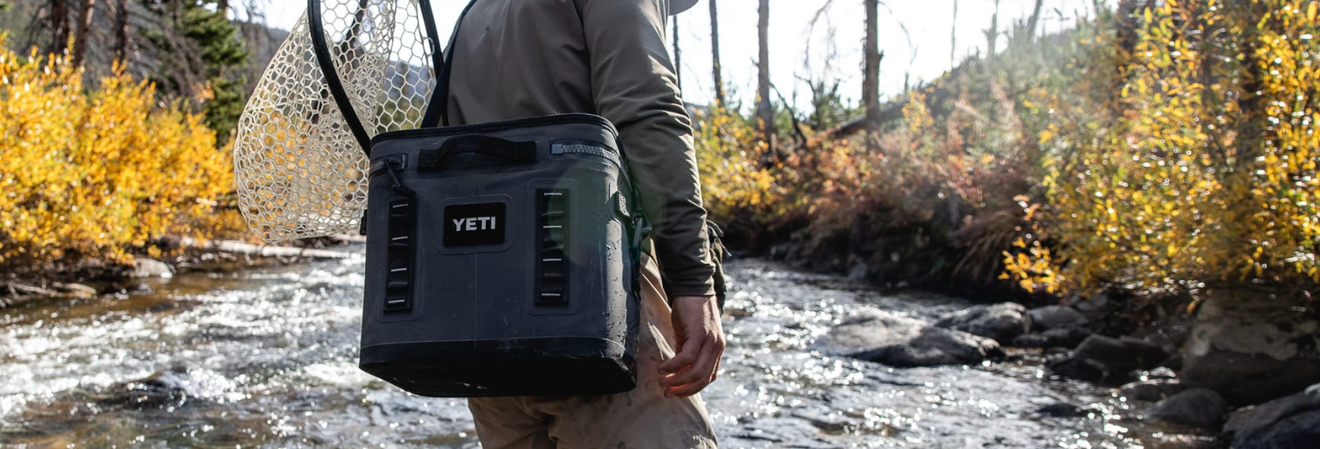 a man with net and YETI cooler in river