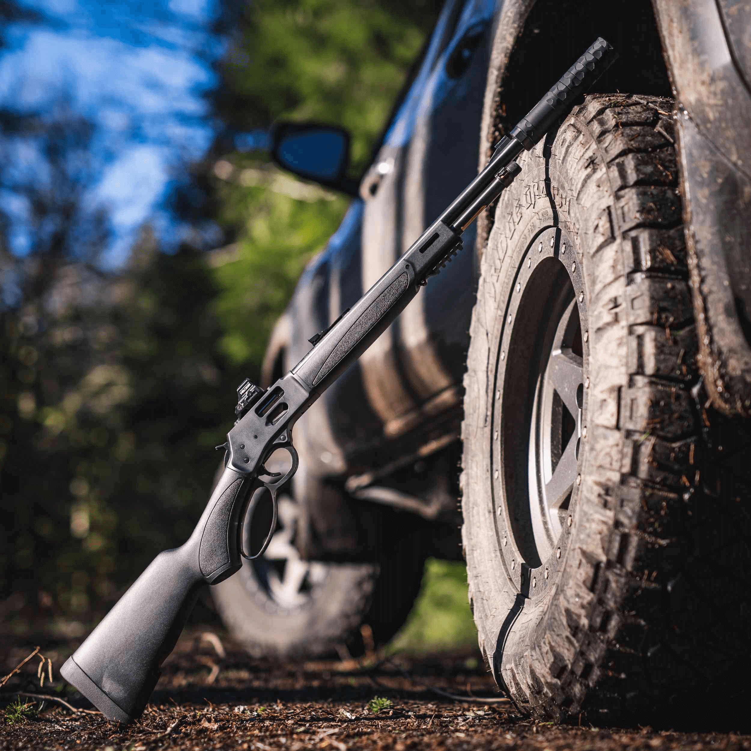 lever action rifle leaning against truck tire