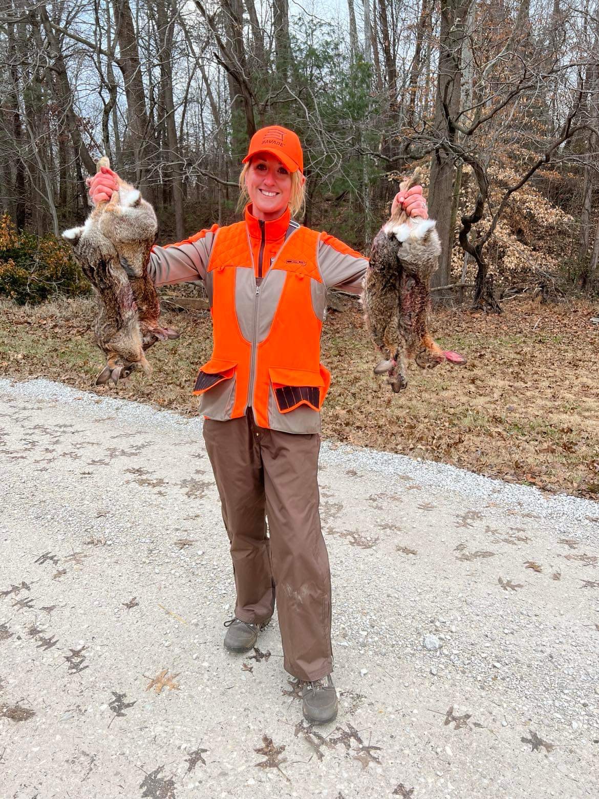 Hunter holding up her hunted rabbits.