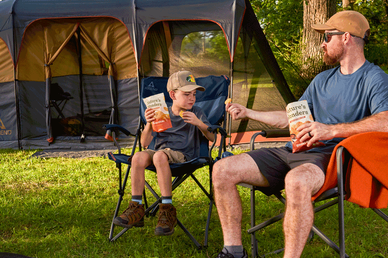 Family enjoying snacks together outdoors at a campsite