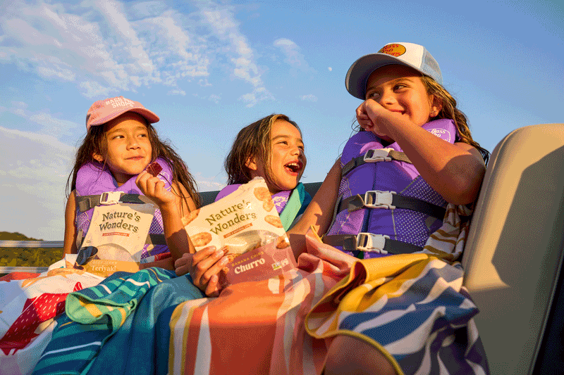Family sharing snacks at a campsite beside a lake